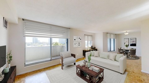 A living room with a white couch, a coffee table, and a large window with blinds.